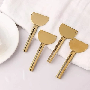 Detailed view of four golden zinc alloy toothpaste squeezers on a white decorative plate