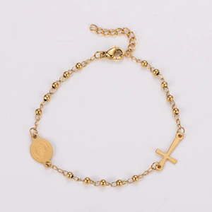 Detail of gold religious bracelet featuring a crucifix cross and Virgin Mary medal charms
