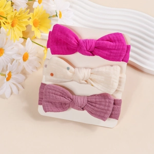 Detailed macro shot of three textured cotton baby bow headbands on a white display card