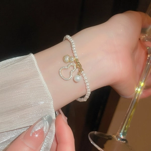 Vue macro du bracelet de perles avec pendentif gourde évidée en or et zircons brillants