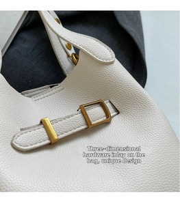 Close-up of pebble-textured cream nylon fabric and matte gold hardware buckle detail