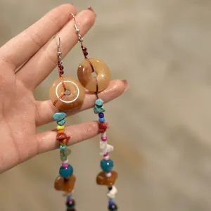 Detail of ethnic earrings with orange resin disks and multi-colored beaded tassels
