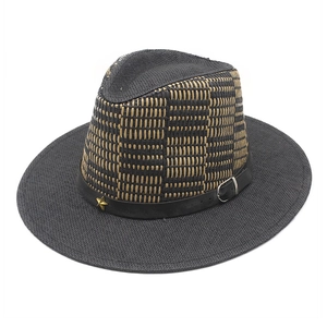 Detail of woven straw hat featuring black yellow plaid pattern and star buckle strap