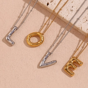 Detail van 18K goud vergulde ballonletterhangers met metallic textuur en een kralenketting