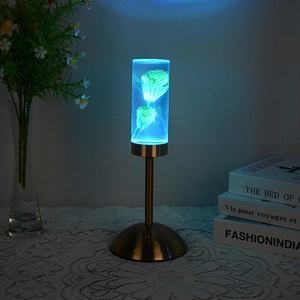 Macro detail of cylindrical acrylic lamp with blue preserved flowers and gold base