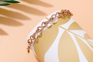 Detailed shot of a rose gold stainless steel S-link infinity chain bracelet in soft light