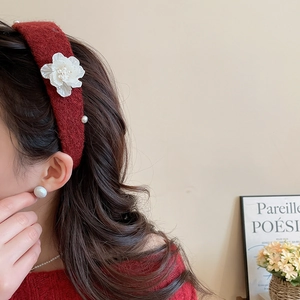 Detail of red knit headband with white floral petals and elegant pearls on a model