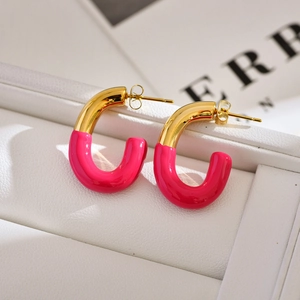 Detailed view of U-shaped gold earrings with bright pink enamel finish on white leather