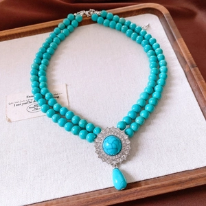 Detail of double-layer turquoise bead necklace with a crystal teardrop pendant