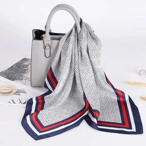 Vista dettagliata di un foulard in raso a righe annodato su una borsa in pelle di lusso
