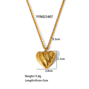Detailed view of the 3D gold heart pendant with vertical ripple texture on a thick chain