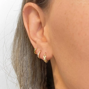 Detail shot of three stacked gold hoop earrings with zircon pavé and chain link design