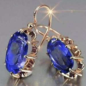 Primer plano de pendientes vintage de oro con gemas azules ovaladas y engastes ondulados