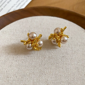 Macro detail of French vintage gold flower earrings with pearls on a rustic linen background