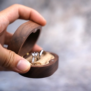 Macro shot of a dark wood ring box with burlap lining holding two diamond rings