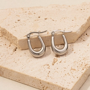 Macro view of polished silver U-shaped hoop earrings on textured stone surface