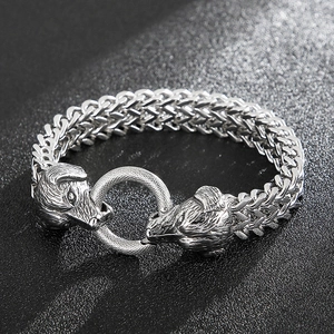 Close-up of vintage silver wolf head clasps on a braided metal men's bracelet