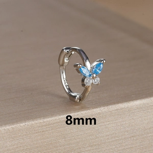 Detail of 8mm silver hoop earring with blue butterfly zircon on a textured background