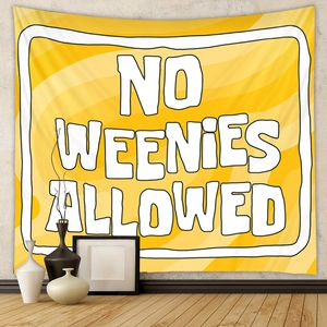 Detail of yellow fabric tapestry featuring bold NO WEENIES ALLOWED text in home setting
