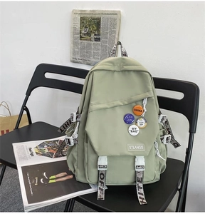 Detail of sage green canvas backpack with multiple pockets on a black chair