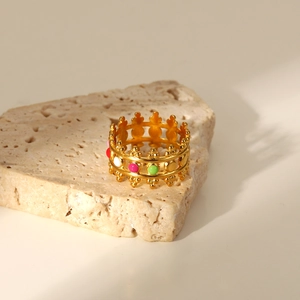 Detail of 18K gold plated crown ring with colorful enamel inlay on stone surface