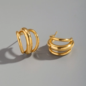 Détail de boucles d'oreilles créoles triples dorées en acier inoxydable poli