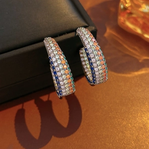 Detail of silver C-shaped hoop earrings with multi-color cubic zirconia stones