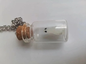 Detail of a glow-in-the-dark ghost inside a glass bottle pendant with silver chain