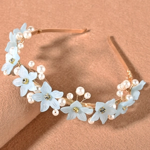 Detail view of gold headband featuring light blue resin flowers and elegant white pearls