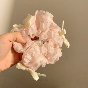 Détail d'un chouchou rose plissé avec bordure en dentelle et nœuds en satin crème