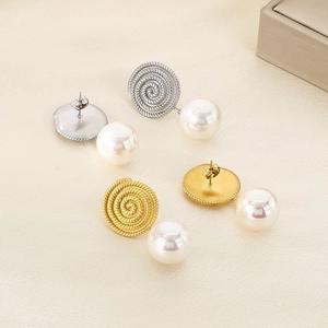 Detailed view of spiral texture gold and silver earrings with elegant hanging pearls