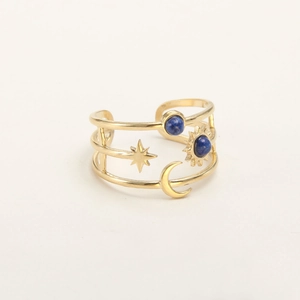 Close-up of gold adjustable ring with blue stones and celestial star moon patterns