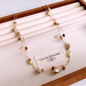 Detail of double-layered necklace with tiger eye beads and irregular pearls in a jewelry box