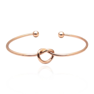 Detail view of a rose gold knotted cuff bracelet with end beads and polished finish
