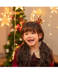 Detail of Christmas reindeer antler headband with pine cones on a smiling young girl