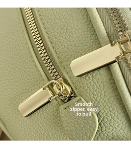 Detail of mint green lychee pattern leather with smooth golden zippers on a crossbody bag