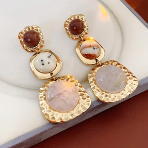 Detail of vintage geometric earrings with gold hammered metal and colorful resin stone