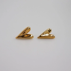 Minimalist gold heart stud earrings with high-polish metallic finish on grey background