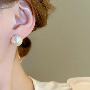 Close-up of matte brushed silver ball earring showing refined metal texture and detail