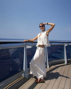 Detailed close-up of white two-piece pleated vacation set on a luxury yacht deck