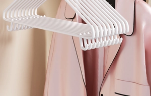 Close-up of white non-slip hangers with hooks for drying pink satin loungewear