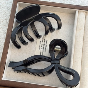 Close-up of elegant black hair claws with gold lettering in a wooden jewelry tray