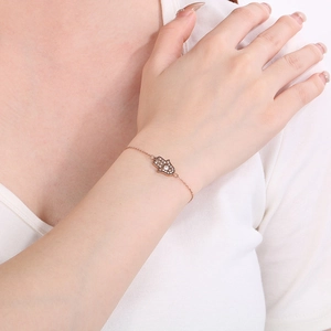 Gros plan du bracelet main de Hamsa en or rose avec cristaux étincelants sur le poignet