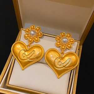 Dettaglio di orecchini vintage a cuore con perle e fiori in una scatola regalo dorata