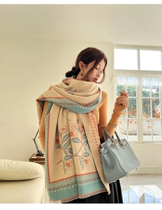 Detail of warm cashmere scarf with orange floral pattern and blue scalloped edges