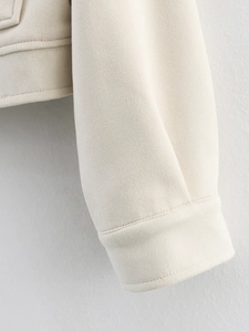 Gros plan des poignets d'une veste en similicuir crème avec coutures et texture épaisse