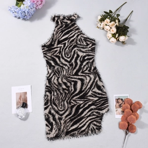 Dettaglio flat lay di un abito attillato zebrato con texture eco-pelliccia e fiori