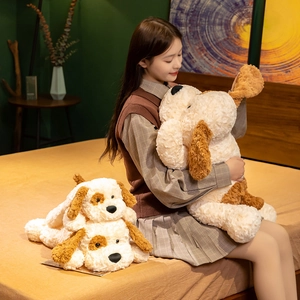 Large huggable plush dog toy with soft curly fur shown in a cozy bedroom scene