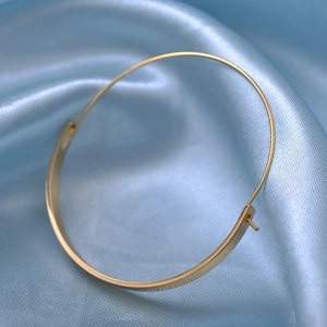 Minimalist geometric half-hoop gold earrings for women on blue silk background