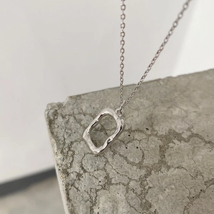 Macro detail of irregular S925 silver pendant on grey stone, minimalist lava texture style